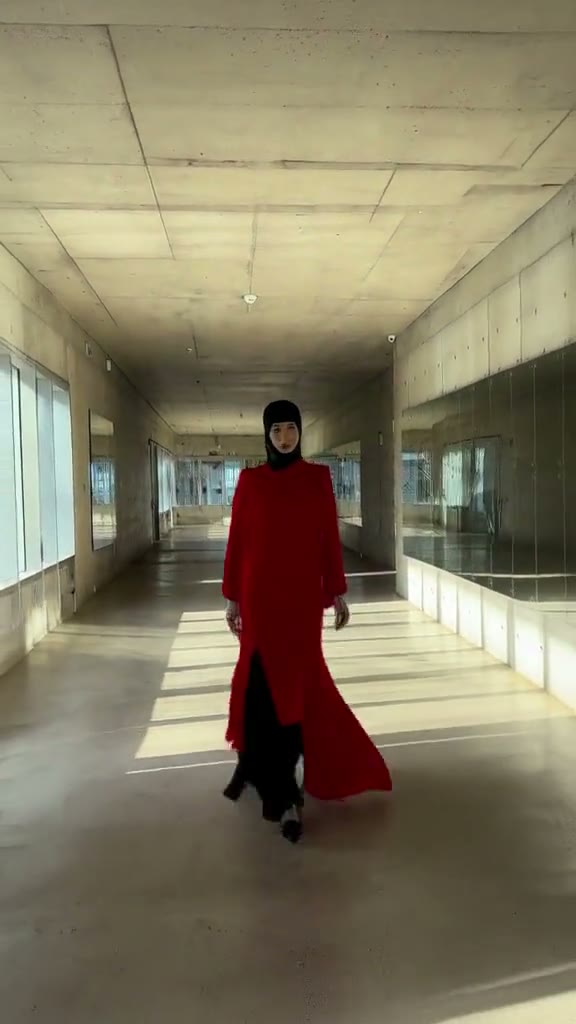 MiniMax H3 output: a model in a red coat walking through a concrete gallery in 9:16