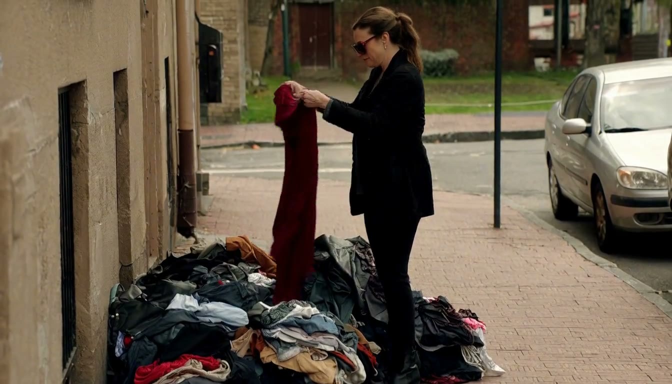 MiniMax H3 AI video example showing a woman is sorting through a pile of clothes on a sidewalk